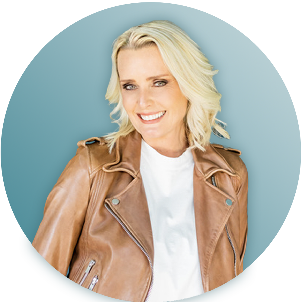 A woman wearing a brown leather jacket and a white shirt is smiling.