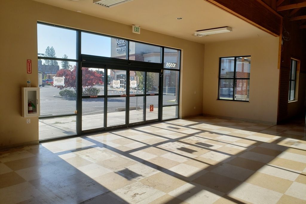 An empty room with a lot of windows and a fire extinguisher