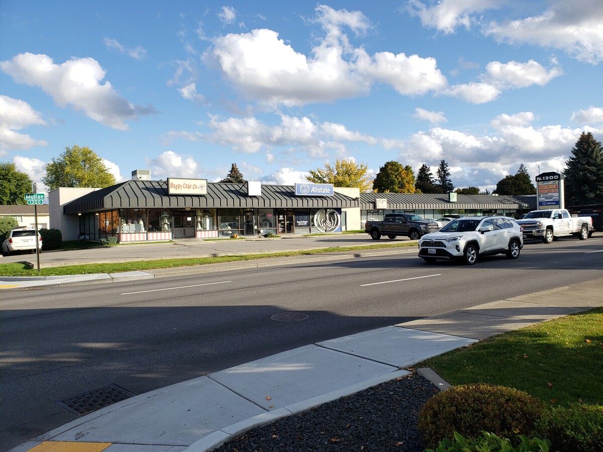 A group of cars are driving down a street in front of a building.