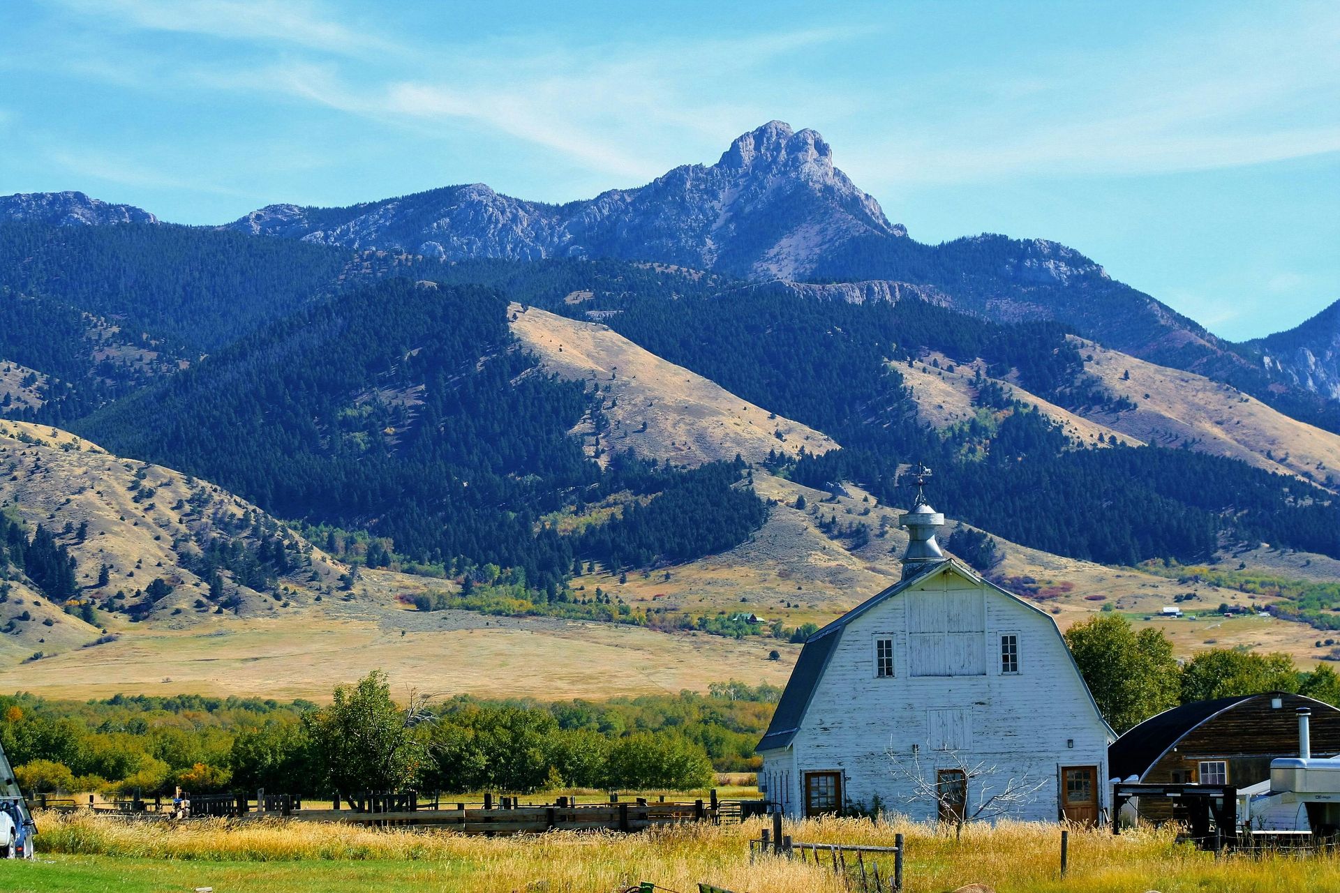 A white barn in a field with mountains in the background