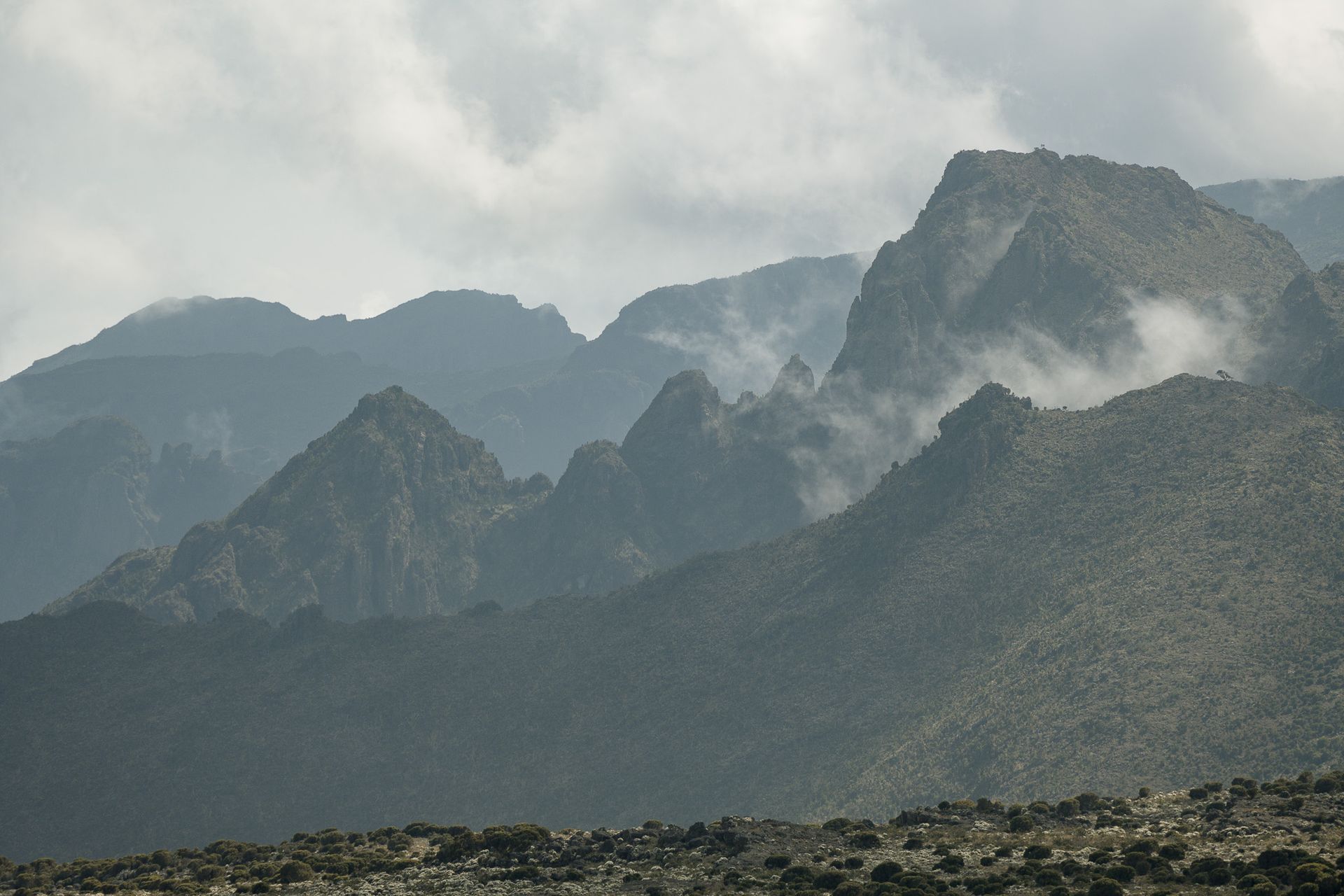 A mountain range with a cloudy sky in the background