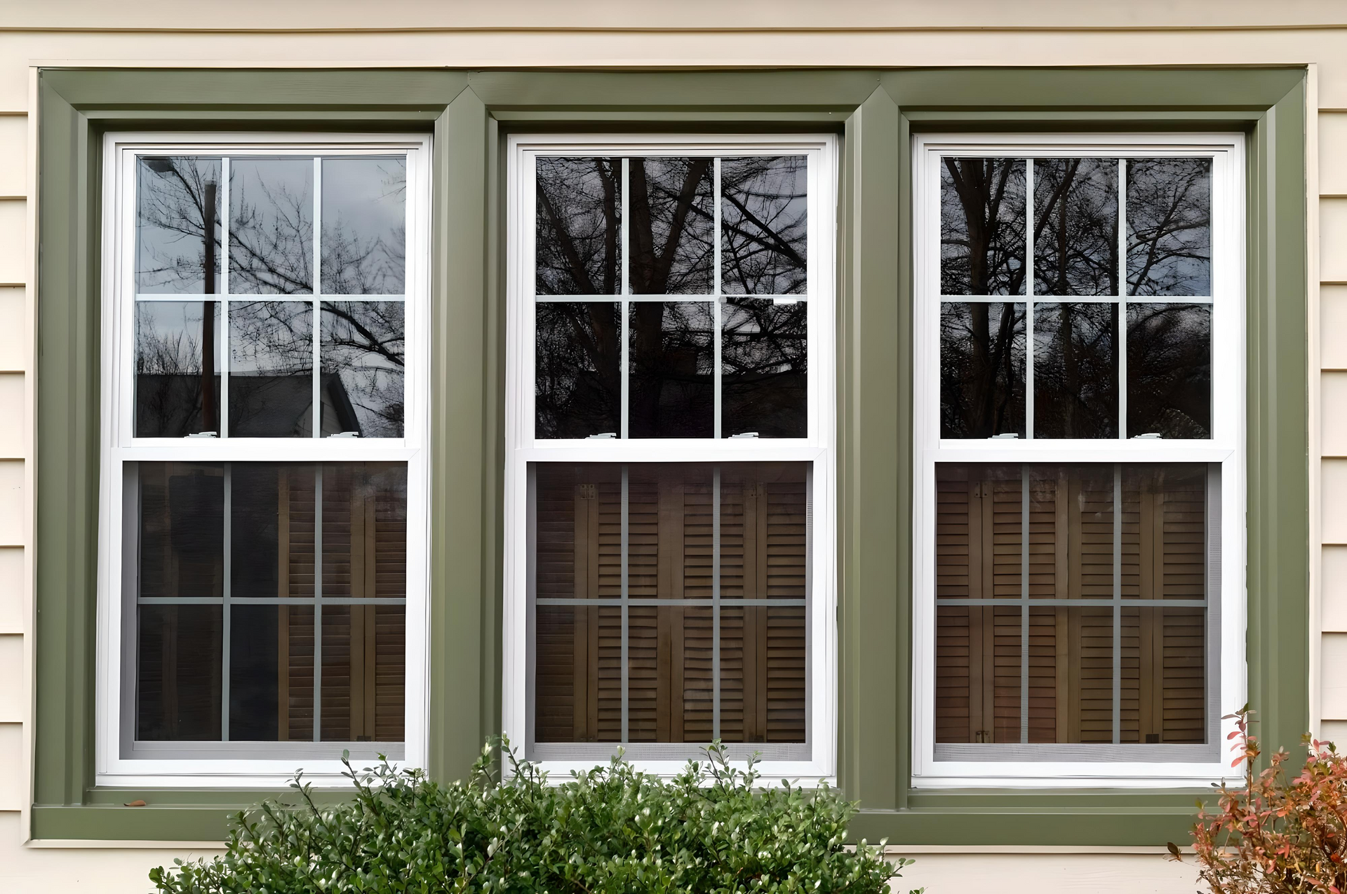 Three windows on the side of a house with green trim