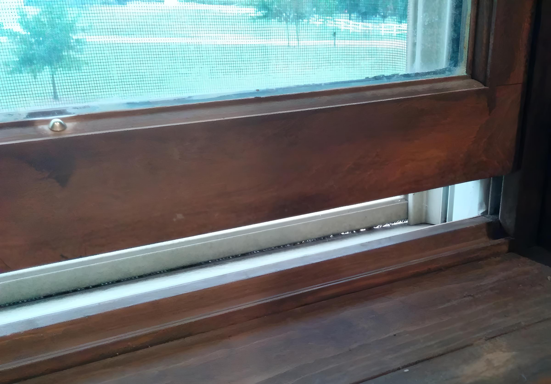 A close up of a wooden window with a broken glass.