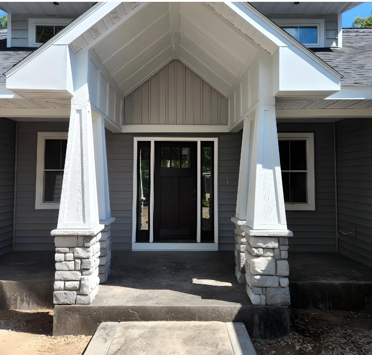 A gray house with a white porch and a black door