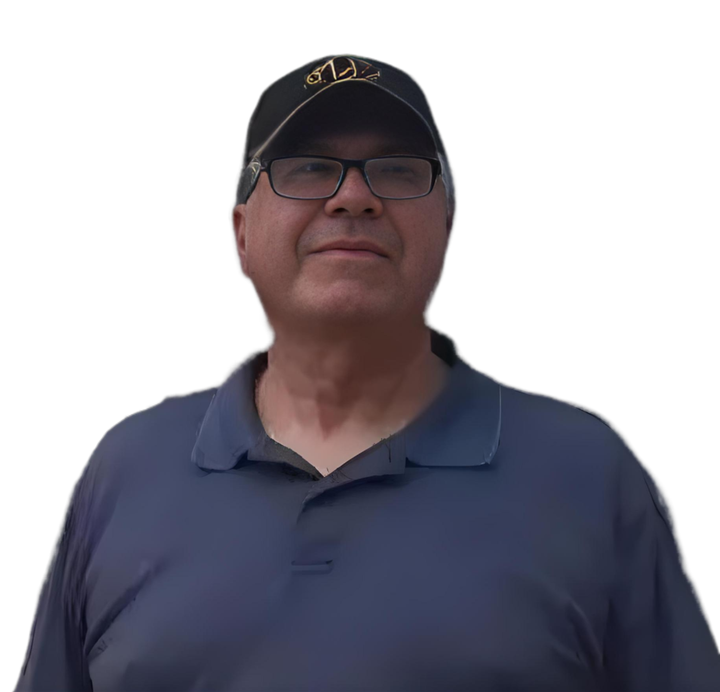 A man wearing glasses and a hat is standing in front of a white background.