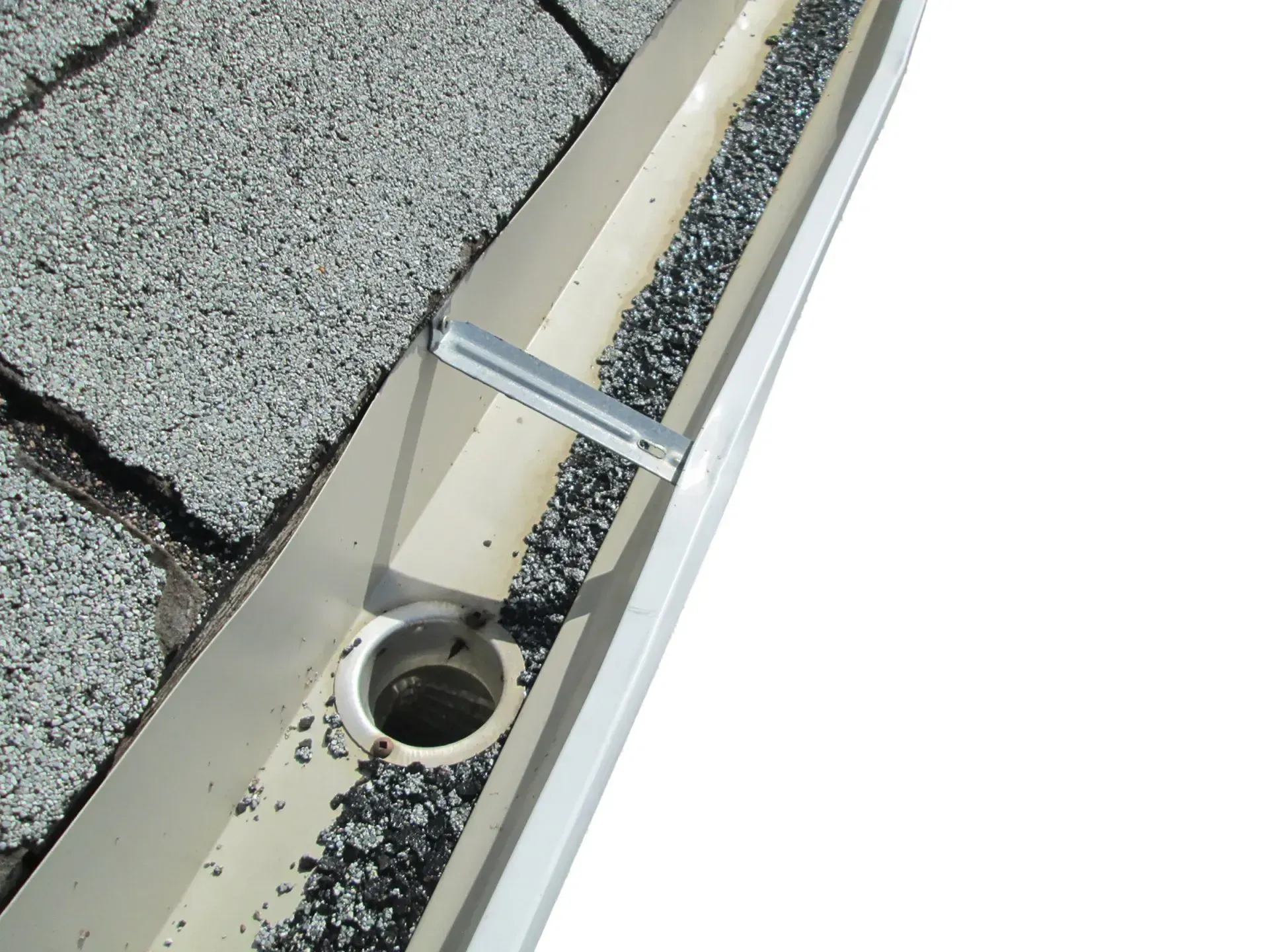 A close up of a gutter on a roof with a hole in it.