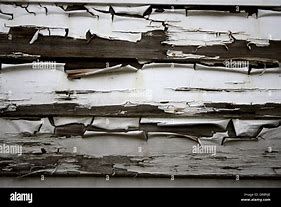 A black and white photo of a wooden wall with peeling paint.