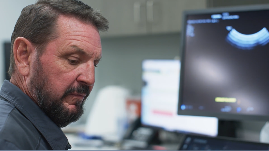 Man examining a monitor showing a medical scan in an office setting