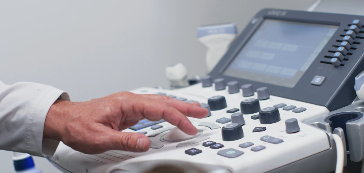 Hand on medical ultrasound machine controls in a clinical setting