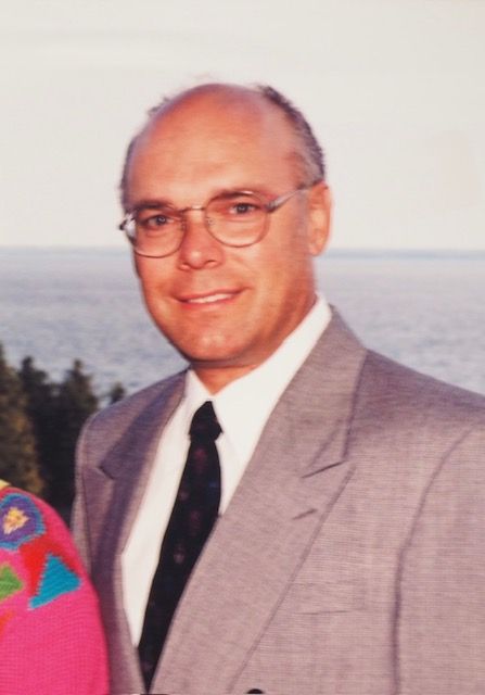 A man in a suit and tie stands next to a woman in a pink sweater