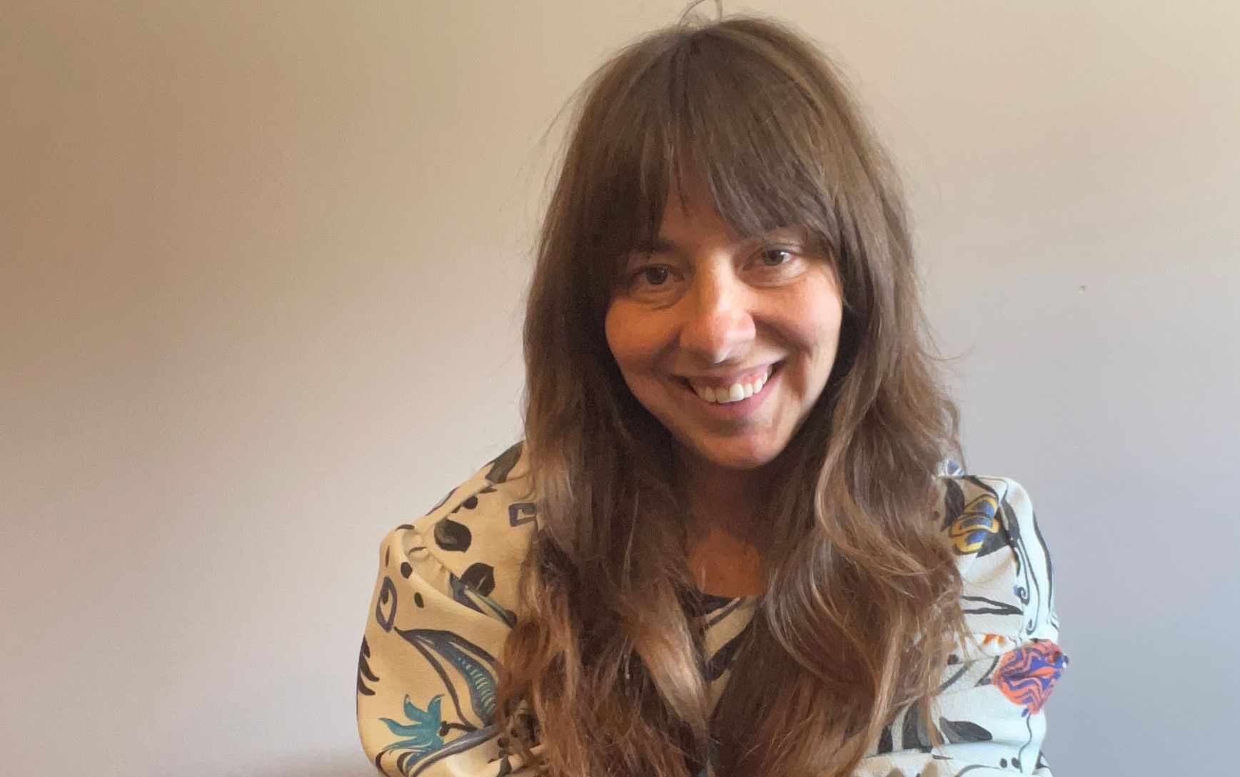 A woman with long hair and bangs is smiling for the camera.