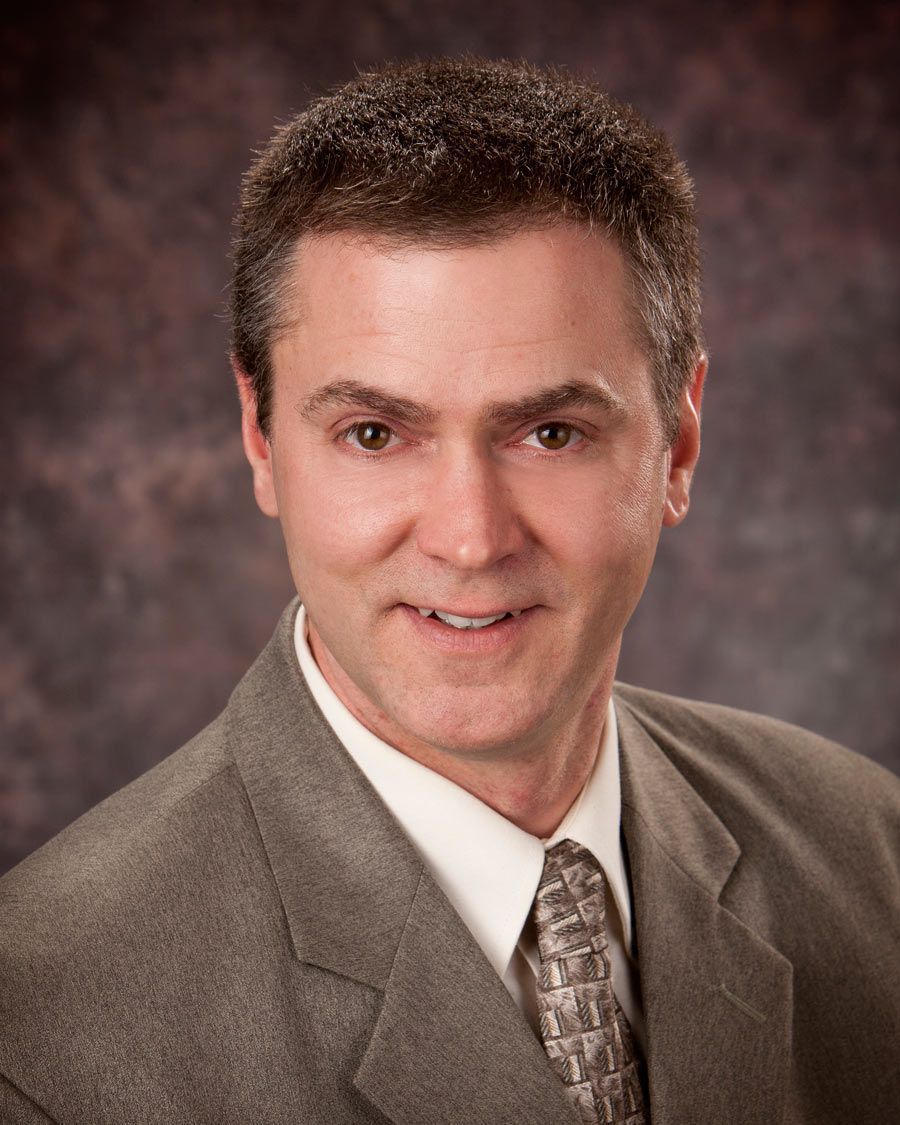 A man in a suit and tie is smiling for the camera