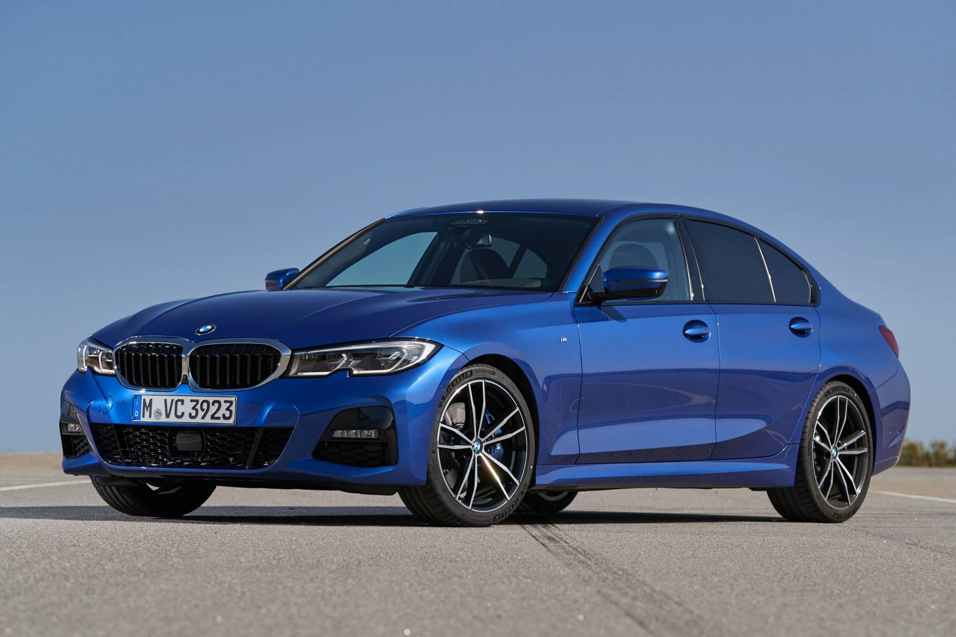 Blue BMW sedan parked on a road under a clear sky, front-left view