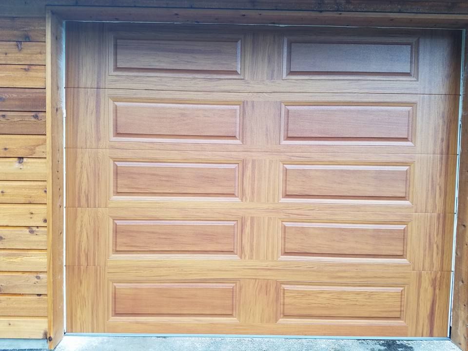 Natural wood garage door with raised panel design