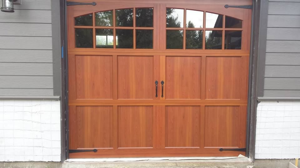 Wood carriage-style garage door with windows and decorative hardware