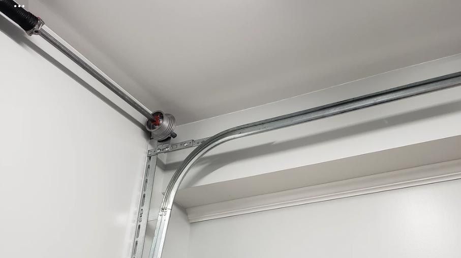 Metal conduit pipes and a circular junction box mounted in the corner of a white room ceiling.
