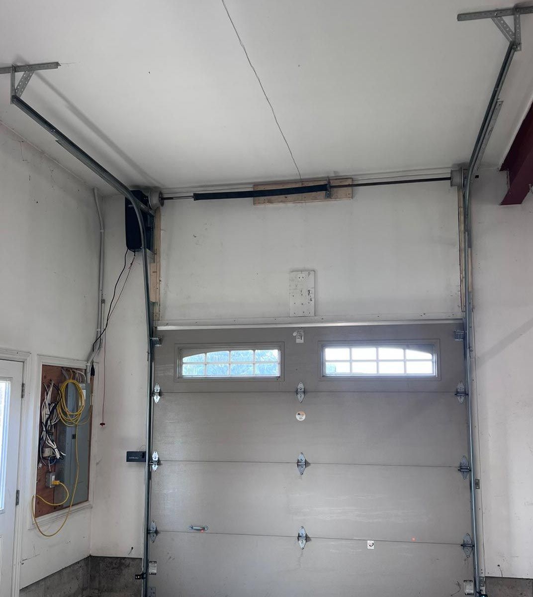 Interior view of a garage door with a wall-mounted jackshaft opener and torsion springs mounted above the door.