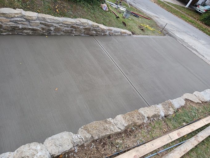 A concrete walkway is being built next to a stone wall.