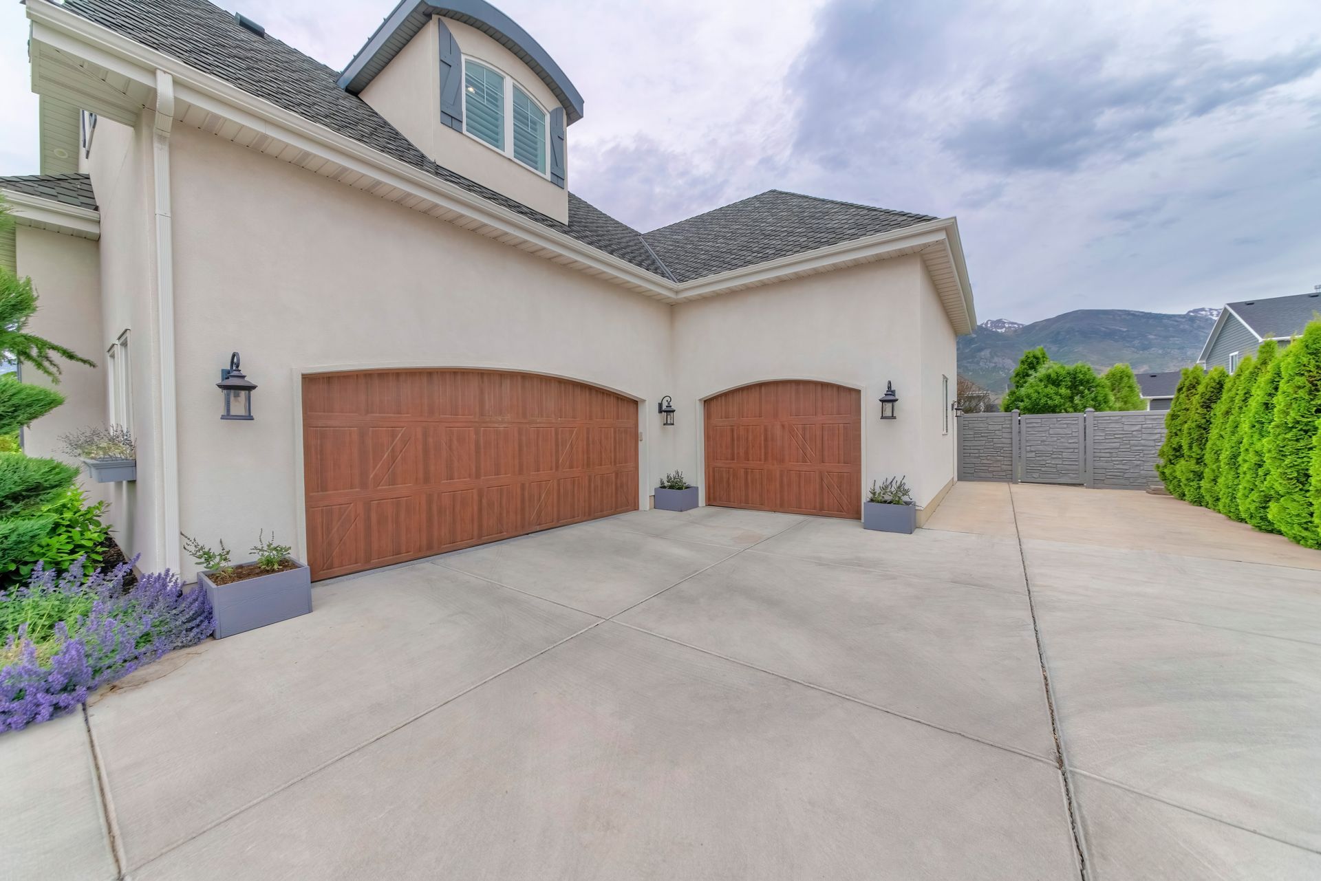 A large white house with two wooden garage doors and a driveway.