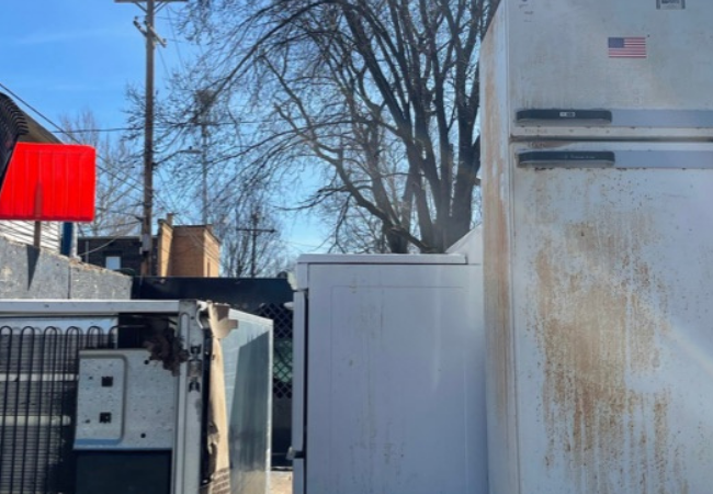 a bunch of appliances in the back of a truck with a tree in the background