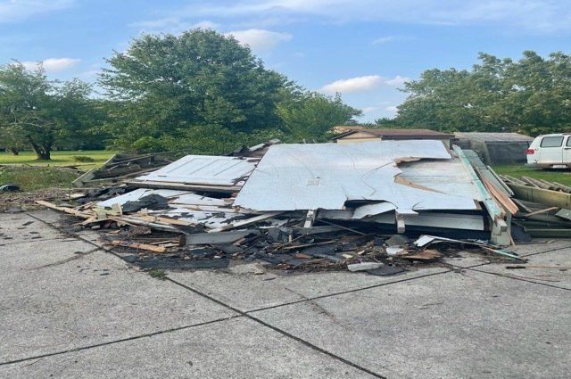 pile of wood and construction debris in a driveway surrounded by trees