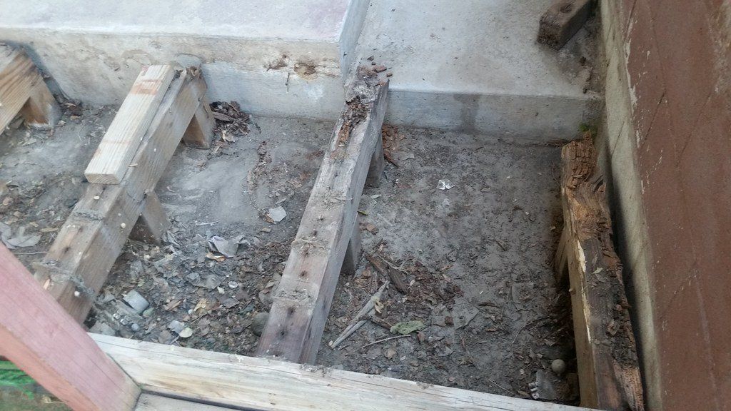 Overhead look at exposed beams from a deck that is currently being removed.