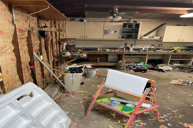 garage filled with junk. garbage on floor and cabinets and shelves.
