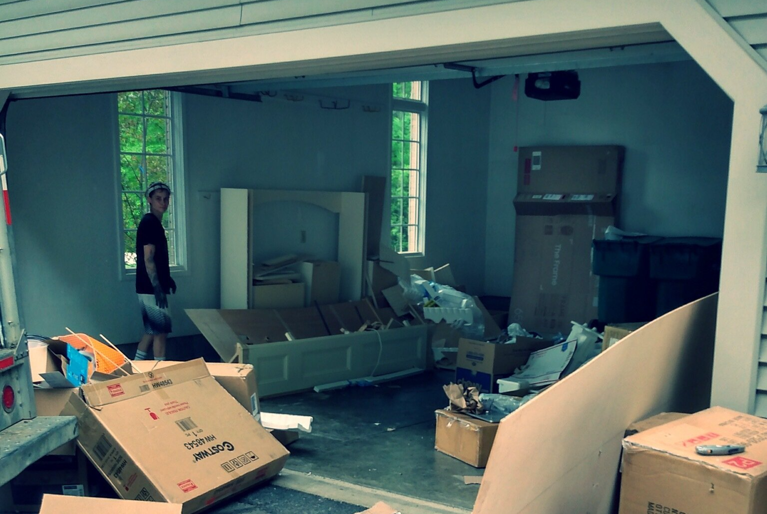 a garage full of cardboard boxes and junk with a person standing inside it