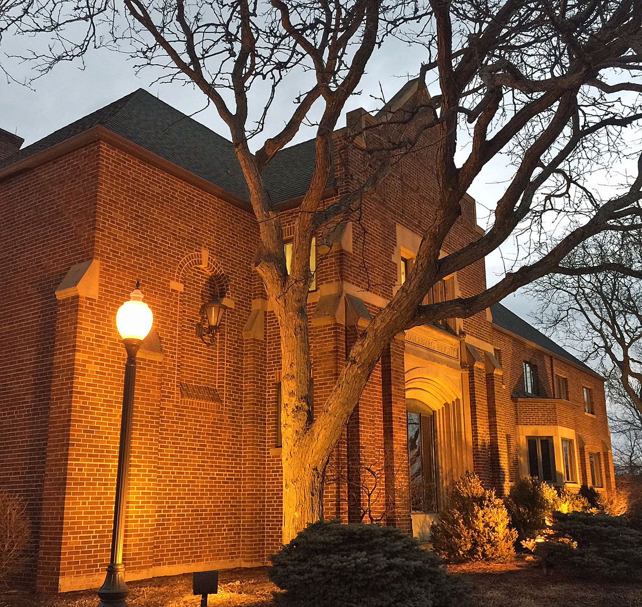 a brick building lit up by a light post with a tree and bushes in front of it in middleburg heights ohio