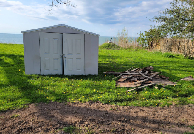 a white shed next to a pile of scrap wood