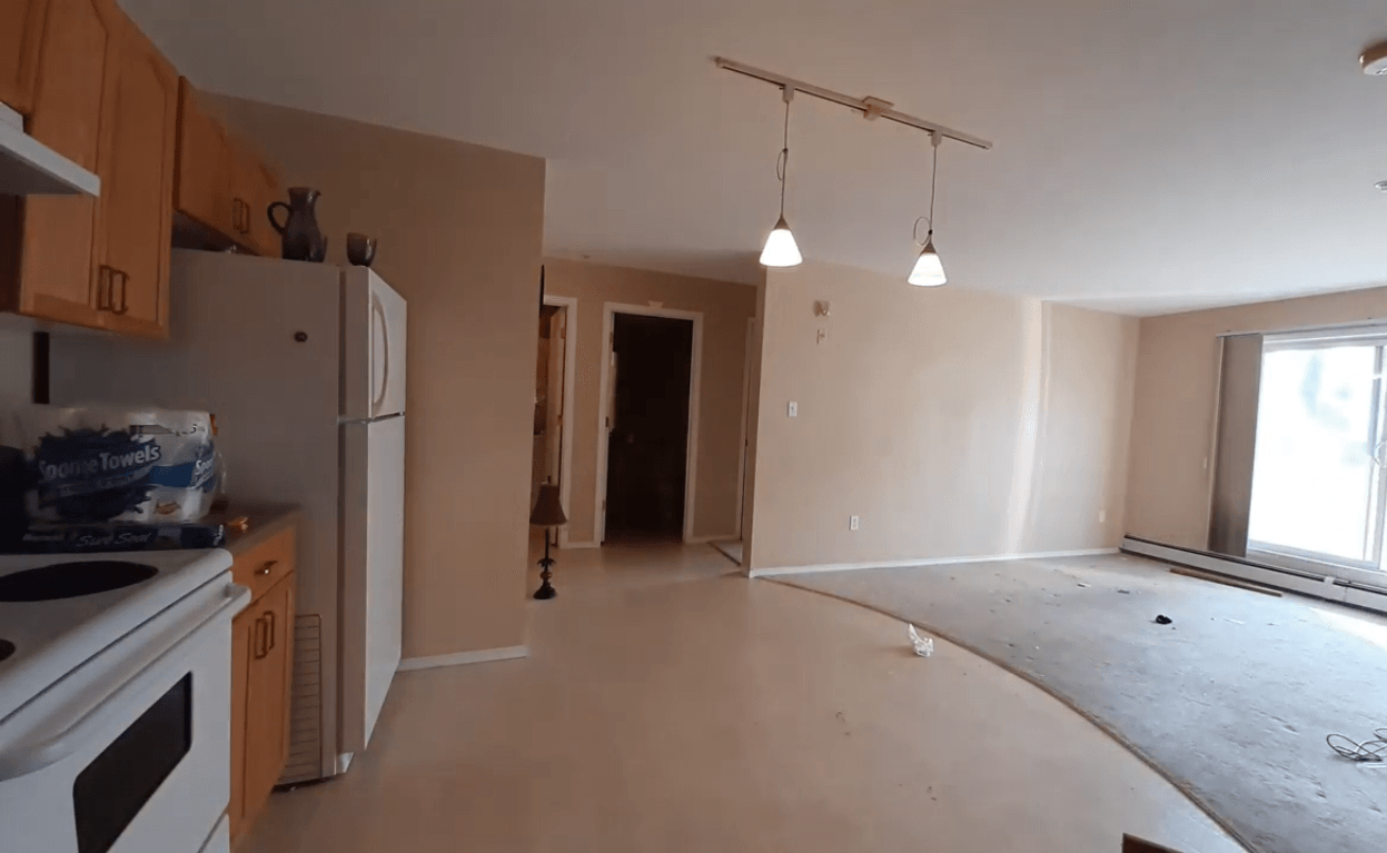 Apartment home left with random items after an eviction. Items such as paper towels, a pitcher (on top of the fridge) and a reading lamp are visible.