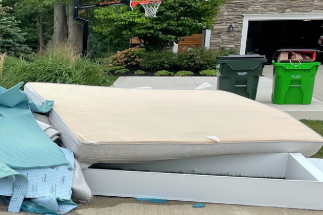 a mattress and a frame on a tree lawn ready for pickup