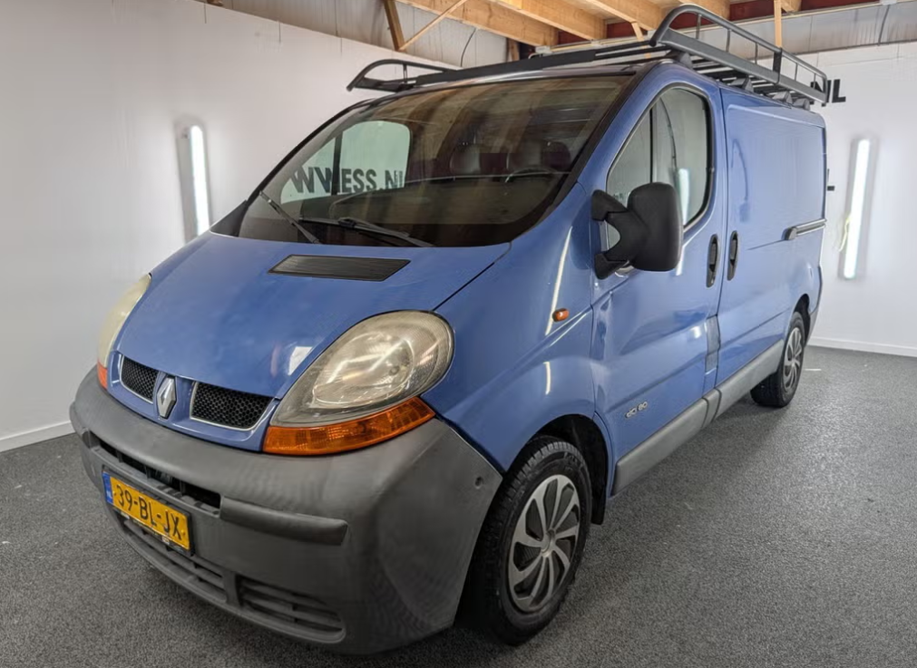 Blauwe bestelbus binnen geparkeerd, vooraanzicht links, met ladderrek op het dak.