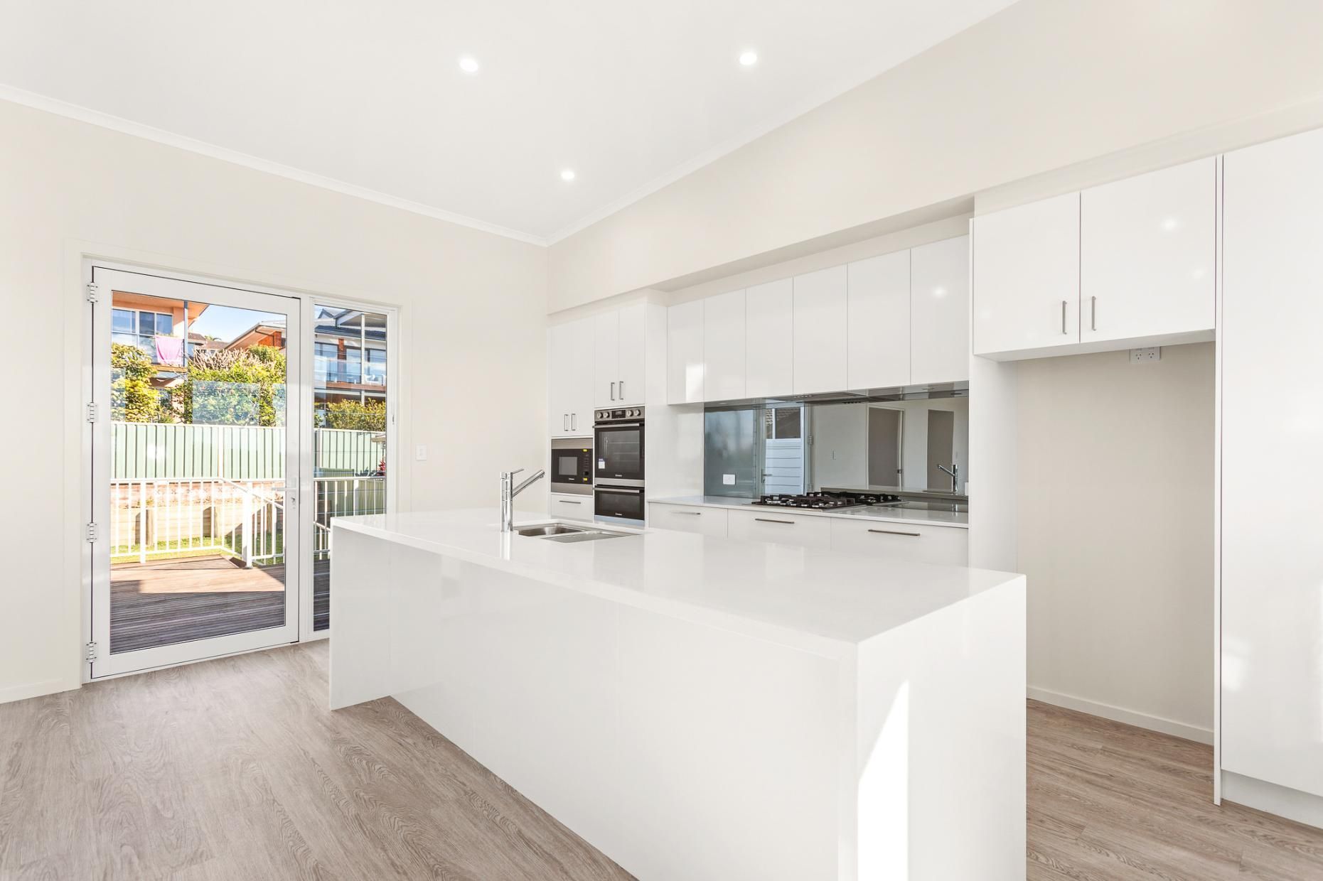 An Empty Kitchen With White Cabinets And A Large Island — Viison Kitchens & Joinery Forster In Old Bar, NSW