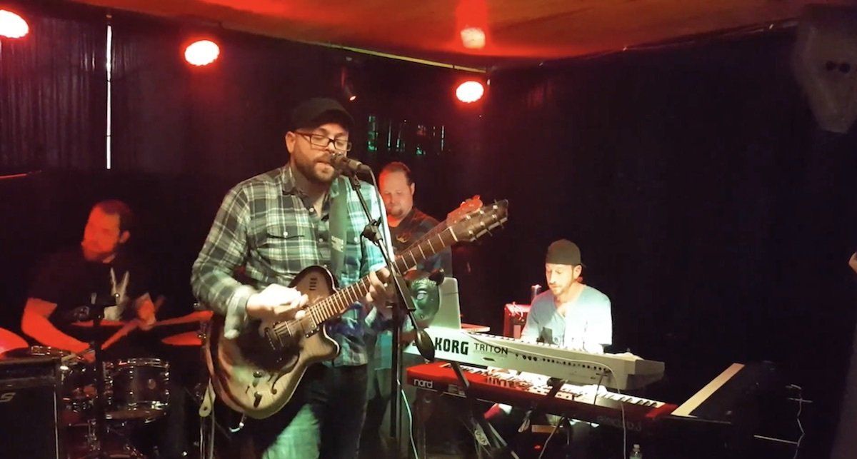 A man singing into a microphone while playing a guitar