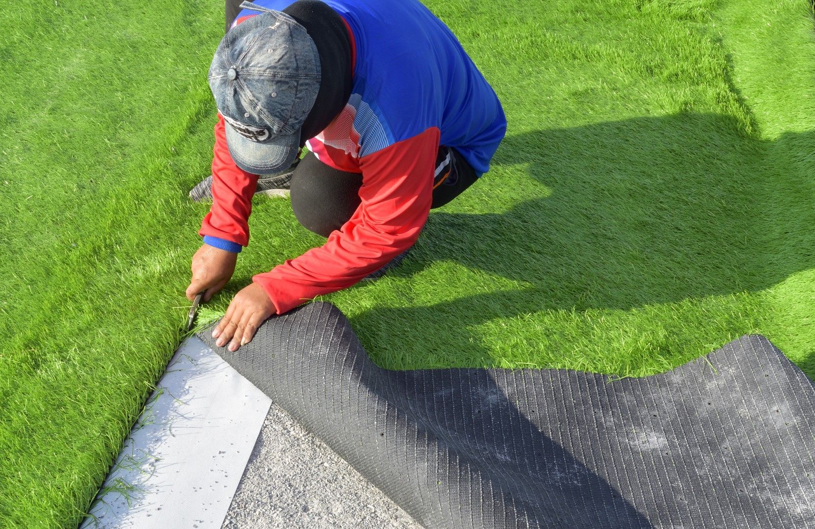 Roll of black landscape fabric on a gray surface, partially unrolled.