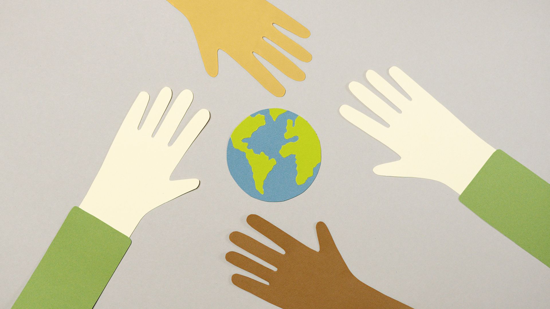 Hands of diverse colors circle a small globe on a light background.