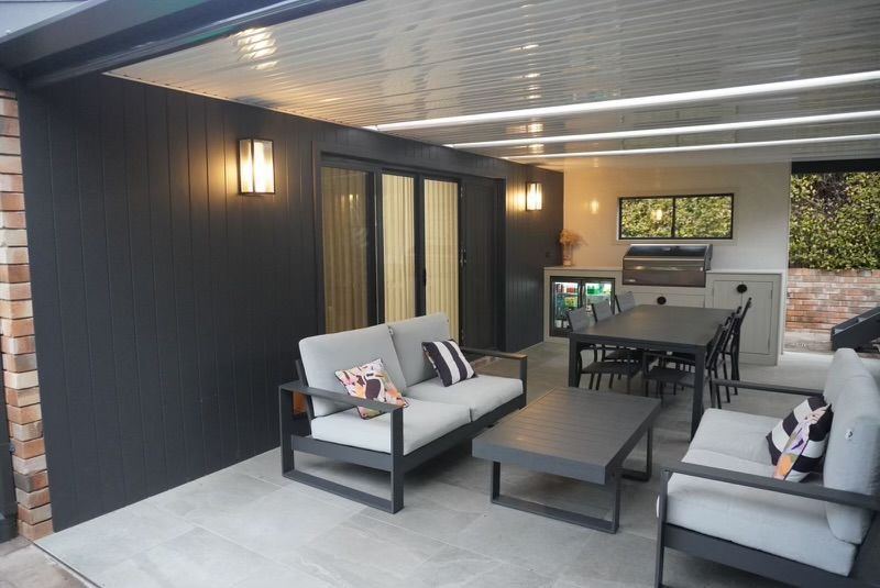 Outdoor patio with dark gray walls, furniture, and a dining area. — Hallam & Sons in Beard, ACT