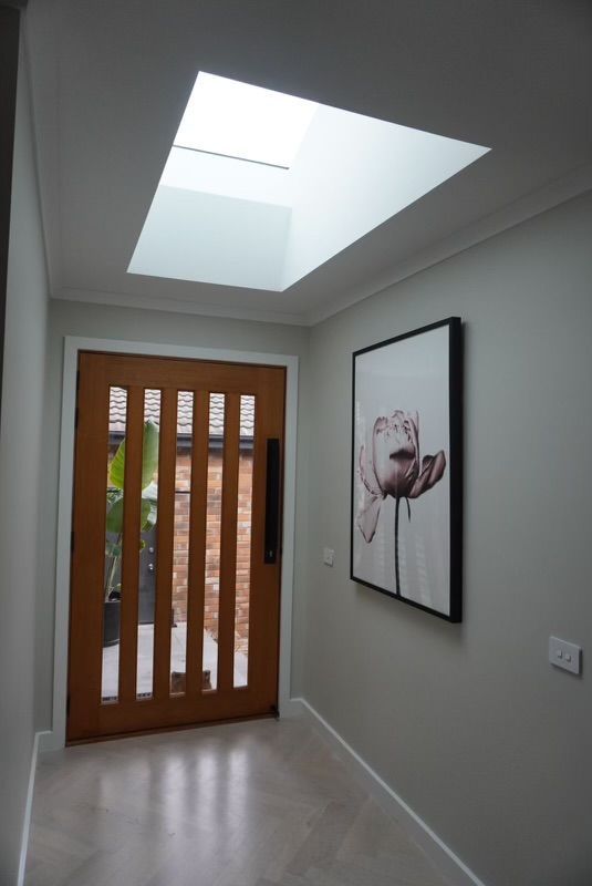 Hallway with wooden door, skylight, artwork, and gray walls. — Hallam & Sons in Beard, ACT