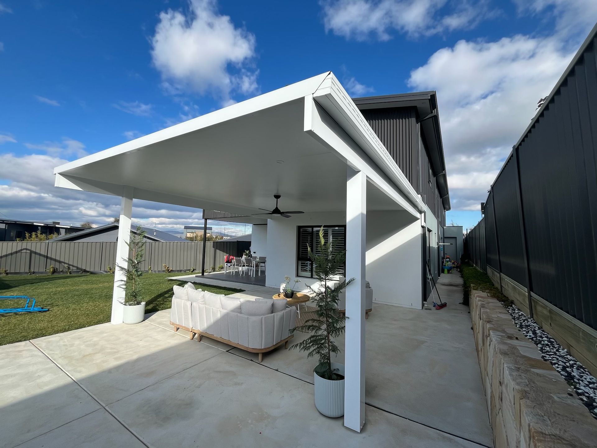 Patio with white roof and columns, outdoor seating, concrete patio, and a backyard. — Hallam & Sons in Beard, ACT