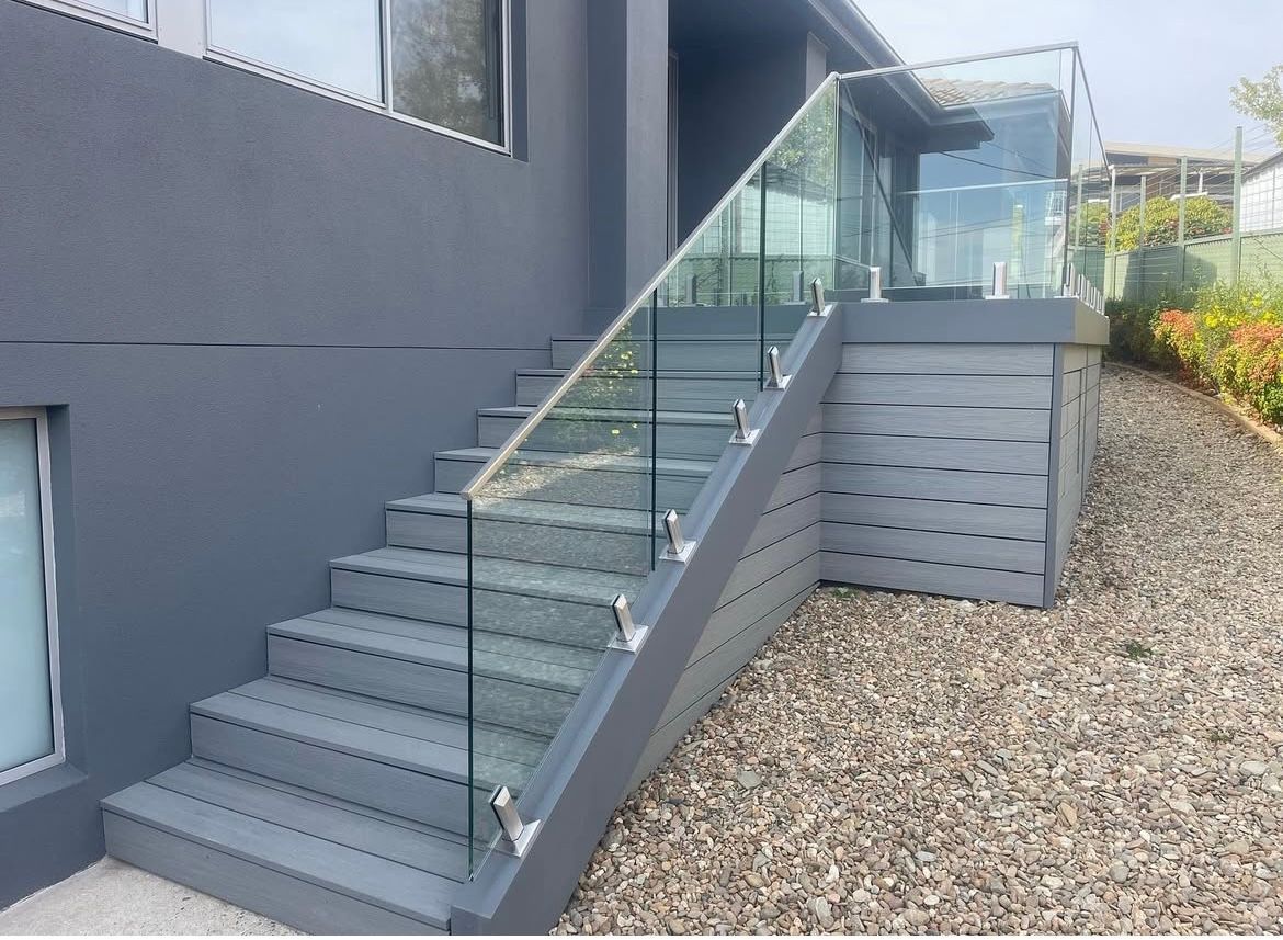 Gray painted stairs with glass railing leading to a deck, gravel ground, and building. — Hallam & Sons in Beard, ACT