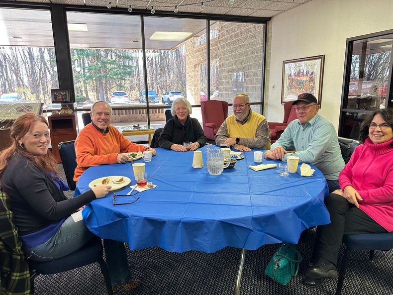 A group of people are sitting around a table with a blue tablecloth.