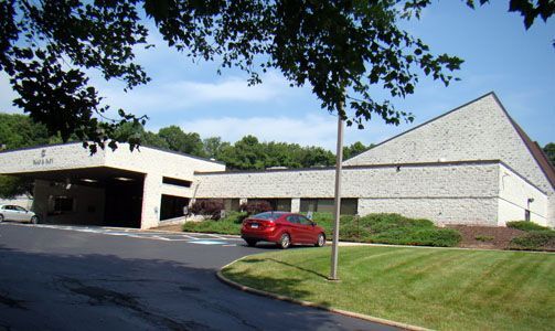A red car is parked in front of a large building