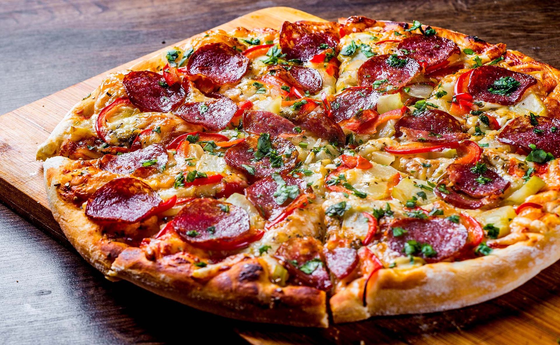 Pepperoni pizza with melted cheese and herbs on a wooden board