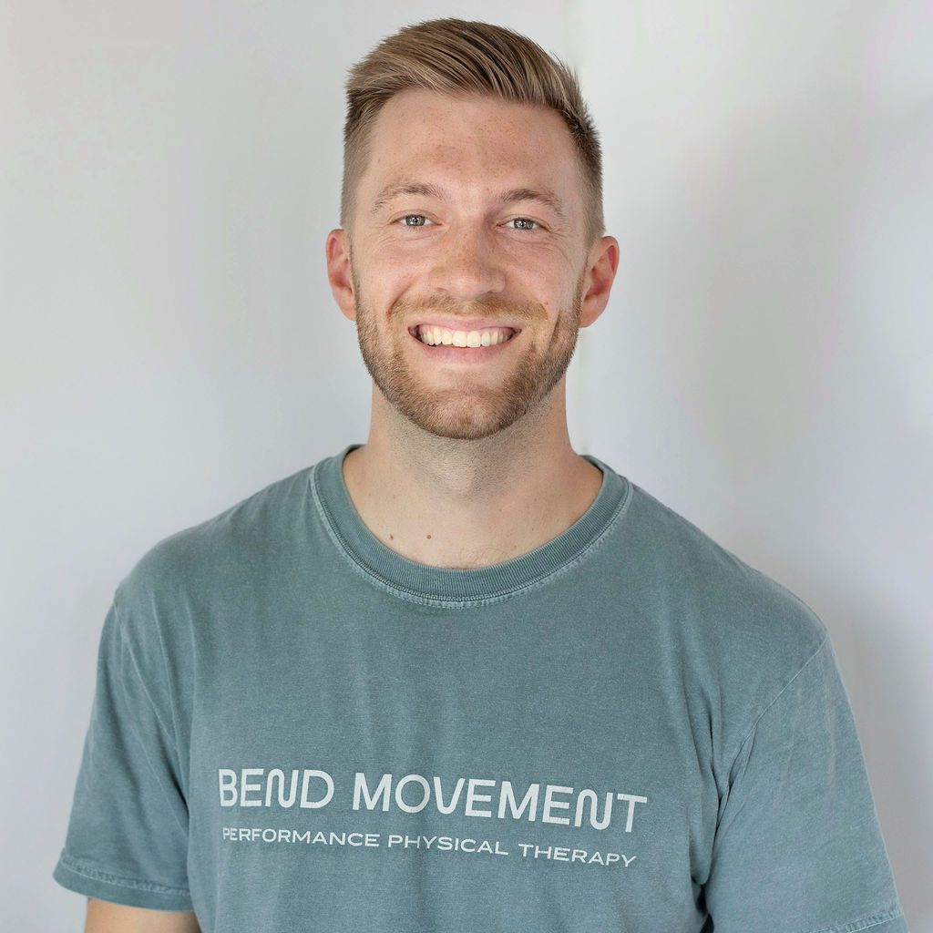 Smiling man in a teal “Bend Movement” T-shirt against a light background