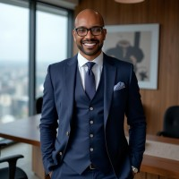 Man in blue suit, smiling, in an office with cityscape view.