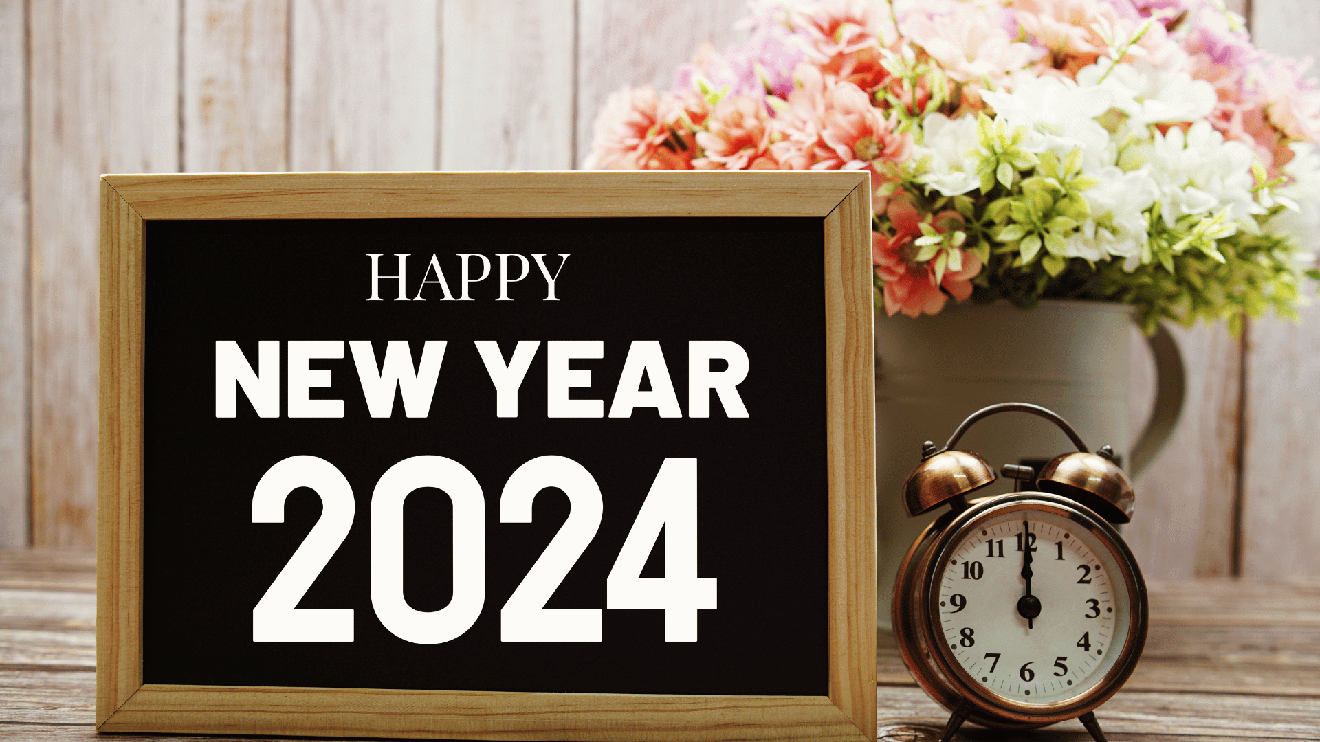 a blackboard with the words `` happy new year 2024 '' next to an alarm clock and a vase of flowers .