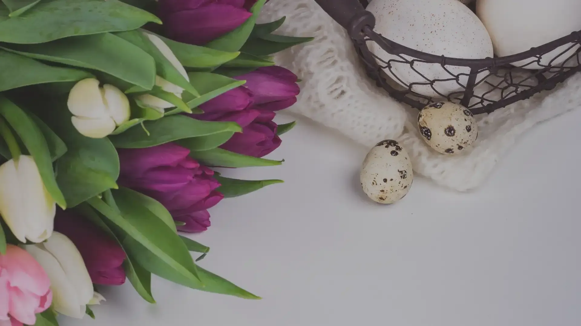 A bouquet of purple and white tulips next to a basket of quail eggs.