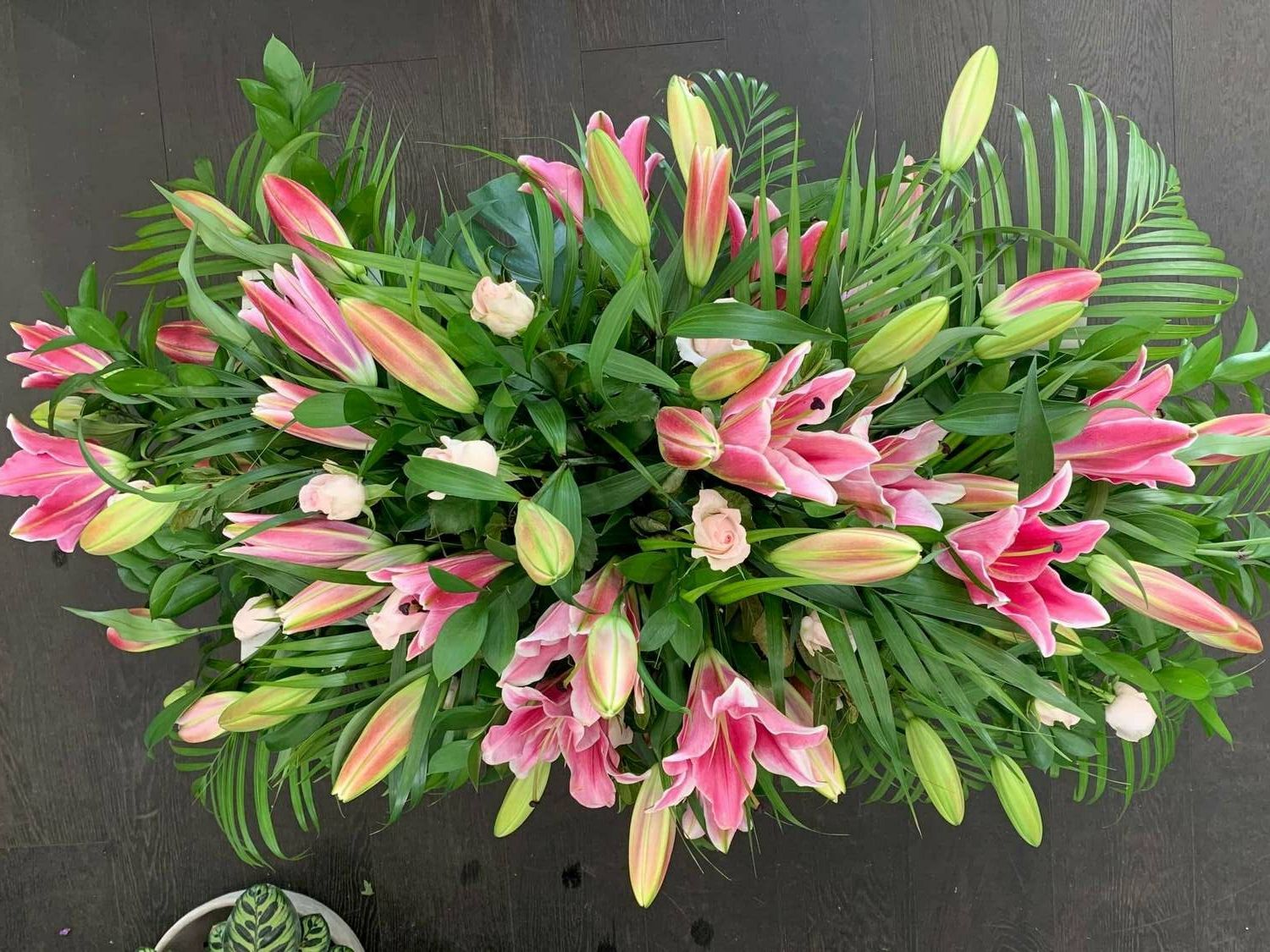 a large bouquet of pink flowers and green leaves on a table .