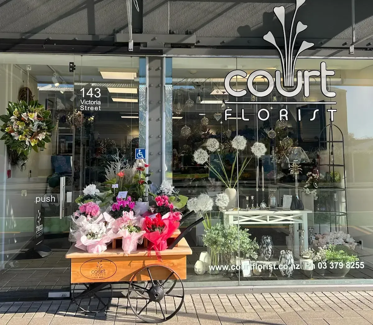 Flower shop storefront with bouquets in front and “Court Florist” sign on the window